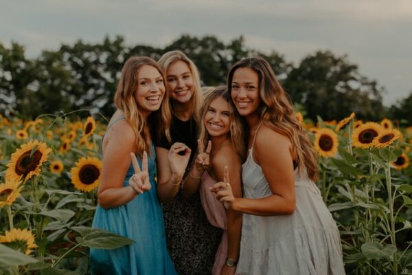 girls posing for picture in front of sunflowers