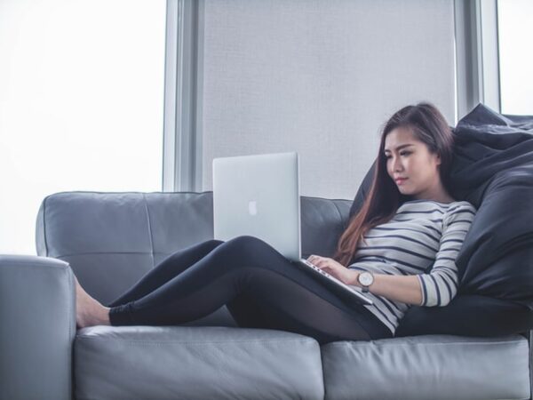 a woman using a laptop laying on a couch